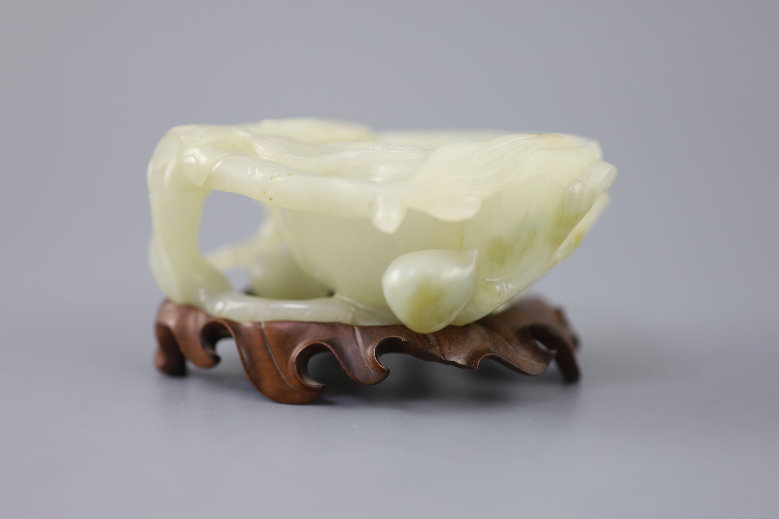 A Chinese pale celadon jade peach brush washer, 17th/18th century 11.3cm at widest point, wood stand